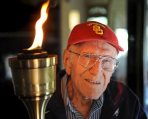 Louis Zamperini, 96, at his Hollywood home. The flame still burns in him as he holds the olympic torch he carried at the 1984 Olympic Games. (Photo by Brad Graverson)