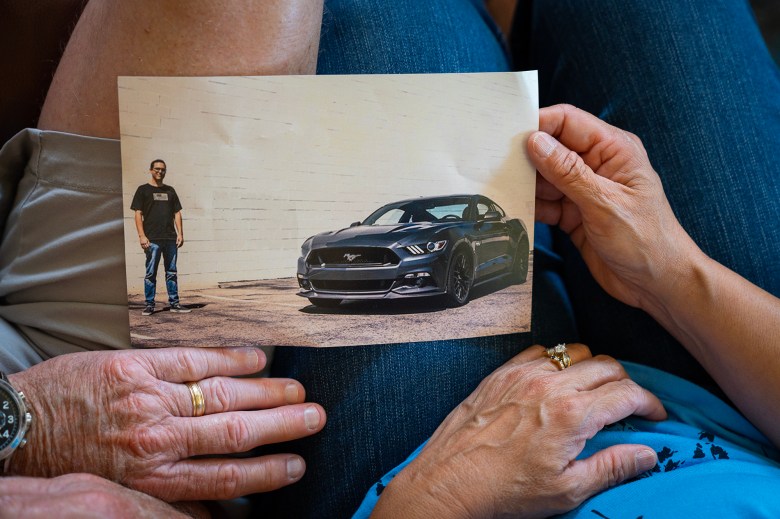 Patti and Glen Balogh hold a photo of their late son, Shane Balogh and his mustang. July 19, 2023. Photo by Julie A Hotz for CalMatters