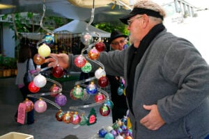 CHECKING OUT THE MERCHANDISE: Ed Broadfield adjusts his display of hand-blown ornaments during the Contemporary Crafts Market at the Santa Monica Civic Auditorium last year. (File photo)