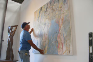 Jose Perez hangs a work by Yossi Govrin at the Santa Monica Art Studios on Wednesday. (Daniel Archuleta daniela@www.smdp.com)