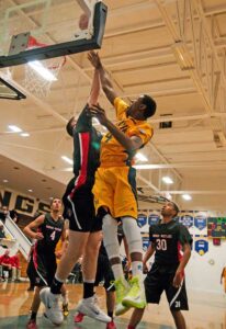 BIG GAME: Samohi's Jonah Mathews (center) leaps into the air to make a layup as Harvard-Westlake defender Bryan Polan tries to block the shot on Wednesday. (Morgan Genser editor@www.smdp.com)