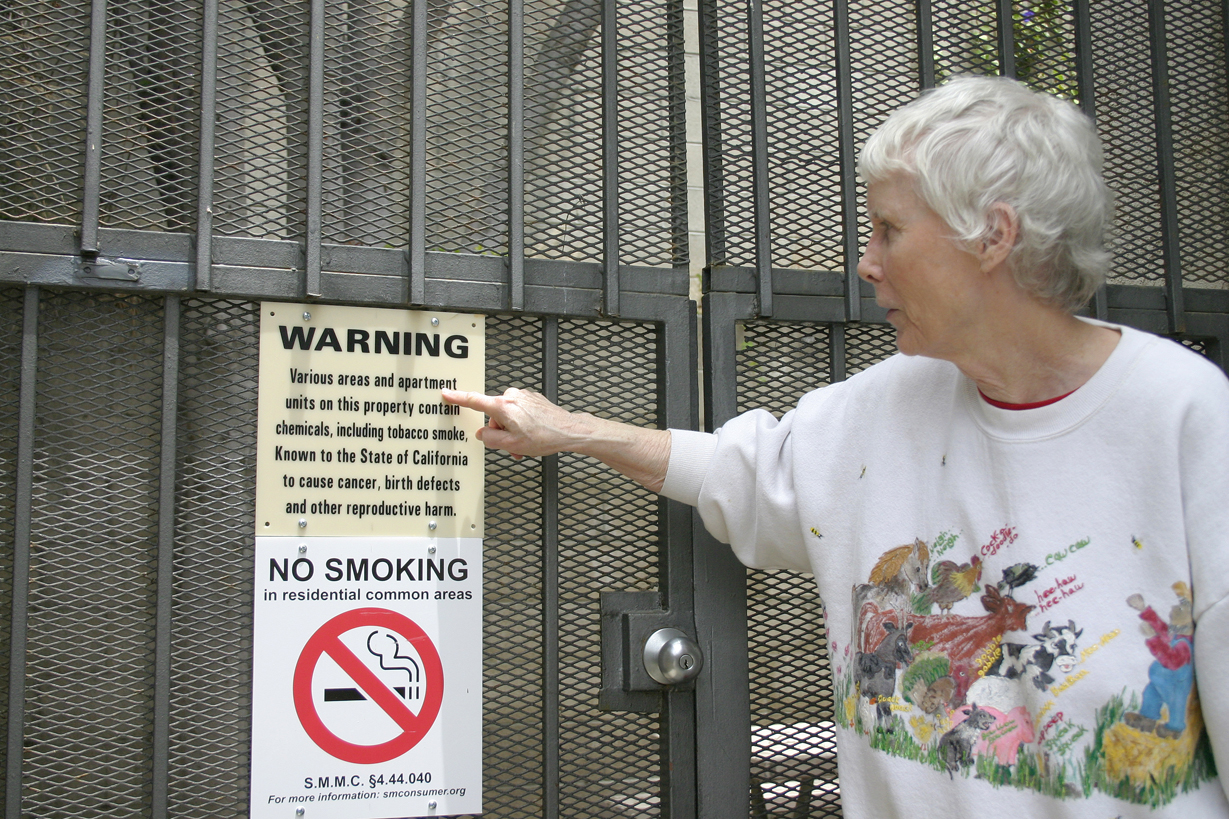 Bette Shapiro points out a 'no smoking' sign at her apartment complex on Fifth Street earlier this year before the City Council voted to ban smoking in apartments and condos for all those moving in after Nov. 22. (File photo)