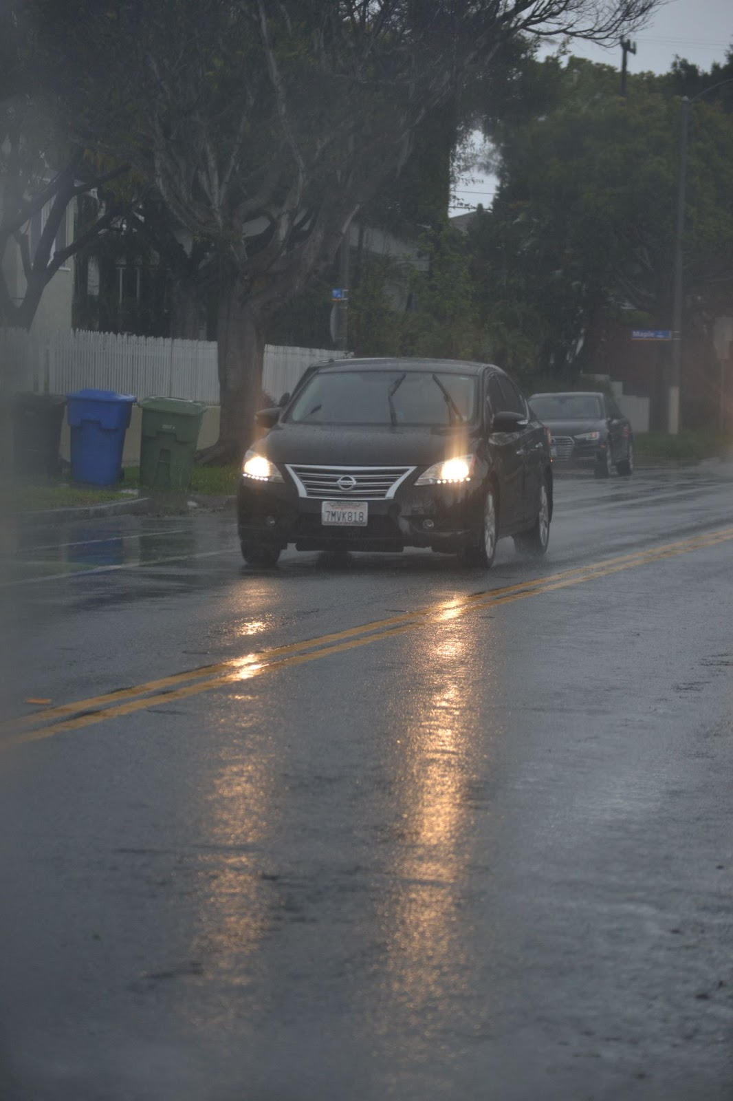 A car driving in Santa Monica under dark, cloudy skies and rain falling