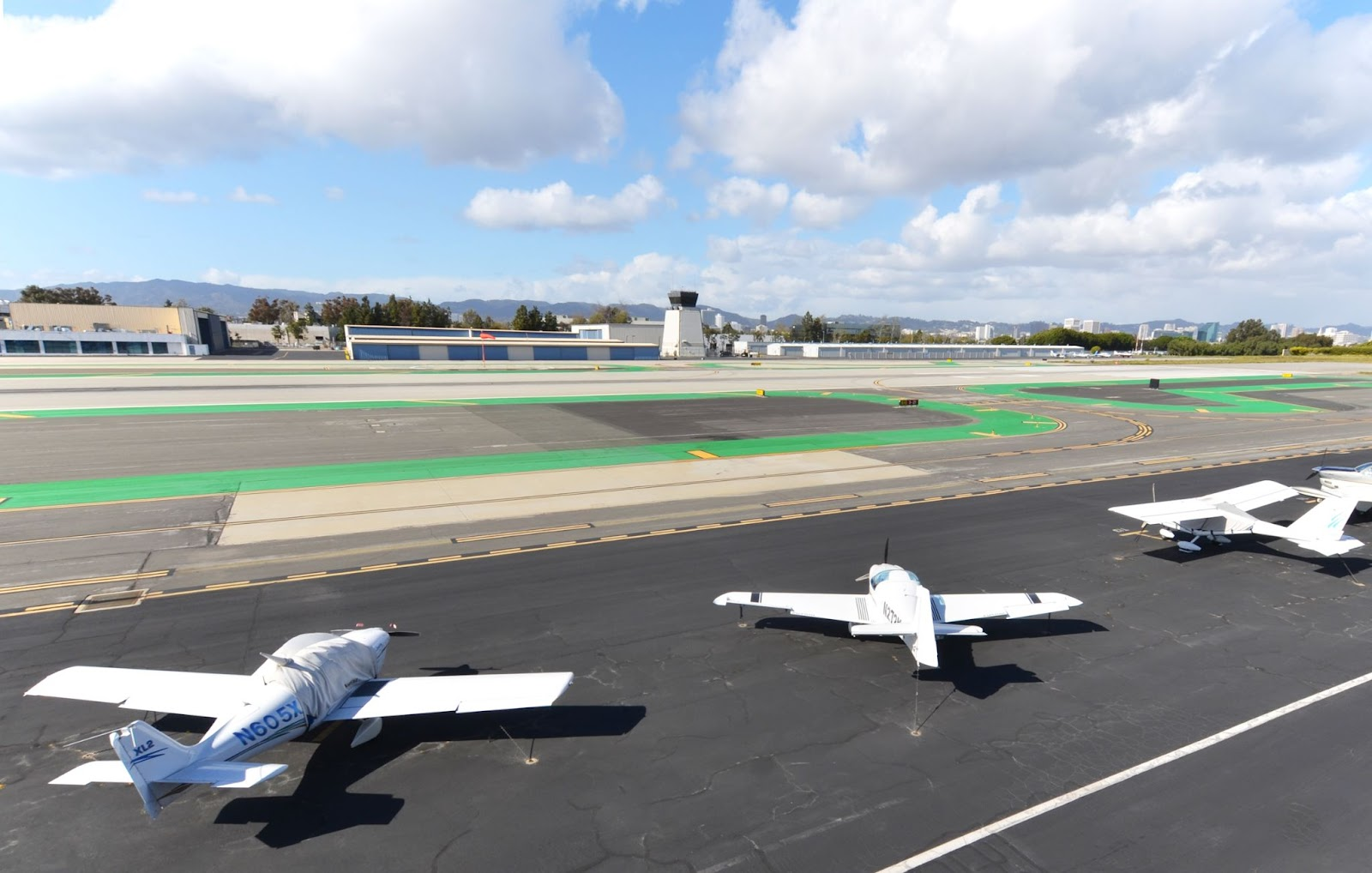 Looking north-west from the main building, across the primary runway, at the control tower of Santa Monica Airport with a few parked, privately-owned planes in the foreground