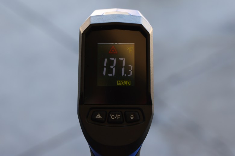 A close-up view of a black infrared thermometer display screen showing the street surface temperature reaching 137.3 degrees.