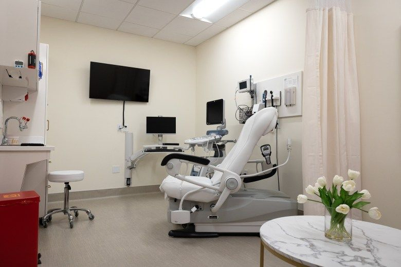 An examination chair surrounded by medical devices inside an examination room at a pregnancy center.